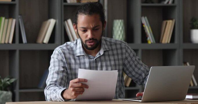 Stressed emotional depressed young african american man reading paper notification with bad news, getting bank loan rejection or dismissal notice, suffering from financial problems or having debt.