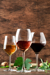Red, white and rose wine in assortment in glasses. Wine tasting, vintage wooden background, copy space
