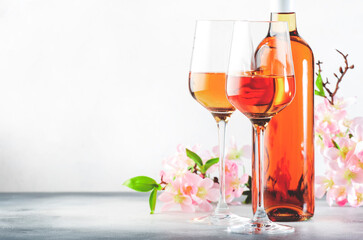 Rose wine glass and bottle on the gray table and pink flowers. Rosado, rosato or blush wine tasting