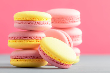 Fototapeta na wymiar Pink yellow macaroons cakes on gray blue table background, place for text, trendy minimalism style, selective focus