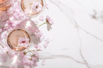Rose light champagne in the two coupes champagne glasses with beautiful soft flowers on the white...