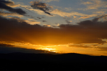 Fototapeta na wymiar colorful cloudy sunset sky over the hill