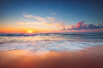 Colorful sunrise over tropical beach and sea with dramatic cloudscape