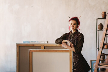 Young smiling woman artist standing in an art studio