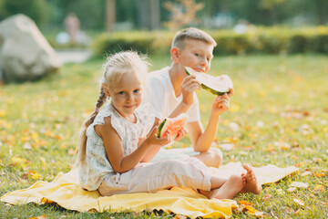 Funny little toddler kids brother and sister eating watermelon on the park. Happy boy and girl...