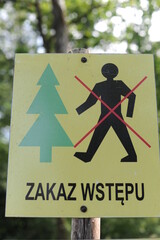 Information sign in Polish “Zakaz wstępu”, English translation “No entry” or “No trespassing” with icons of a person and a tree forbidding an entry to the forest