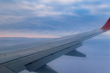 Fototapeta premium a view from a height above the clouds from the plane's window. part of an airplane wing in the frame