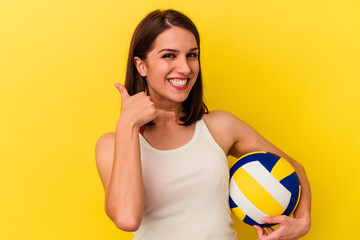 Young caucasian woman playing volleyball isolated on yellow background showing a mobile phone call gesture with fingers.