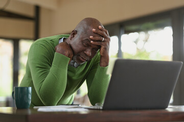 Stressed senior african american man in modern kitchen making video call