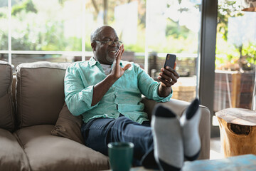 Happy senior african american man siting on couch and making video call in the modern living room