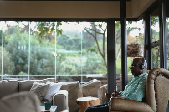 Relaxing senior african american man using headphones in the modern living room