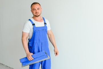 A man processes the wall with a spatula. Plasterer at work.