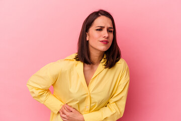 Young caucasian woman isolated on pink background having a liver pain, stomach ache.