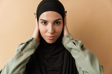 A portrait of the positive muslim woman covering her ears