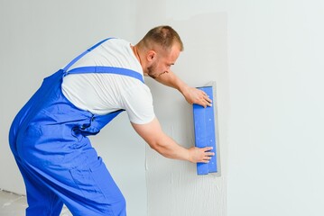 A man processes the wall with a spatula. Plasterer at work.