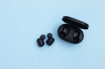 Obraz na płótnie Canvas Wireless headphones or earbuds with charging case on bright blue background.