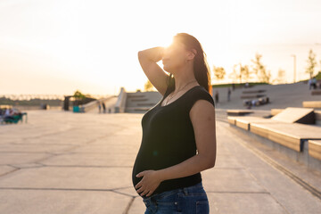 Hispanic pregnant woman relaxing and enjoying life outdoor with copy space. Pregnancy and motherhood concept.