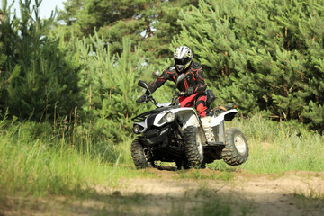 Fototapeta na wymiar Man driving modern quad bike on sandy road near forest. Extreme sport