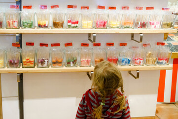 Little preschool girl in candy shop. Cute happy toddler child buy different bonbons and lollipop in a store.