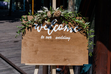 Board, which stands on the grass with wedding inscription Welcome to our wedding. Mockup for...