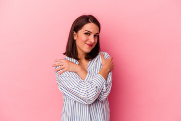 Young caucasian woman isolated on pink background hugs, smiling carefree and happy.