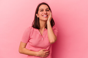 Young caucasian woman isolated on pink background laughs happily and has fun keeping hands on stomach.