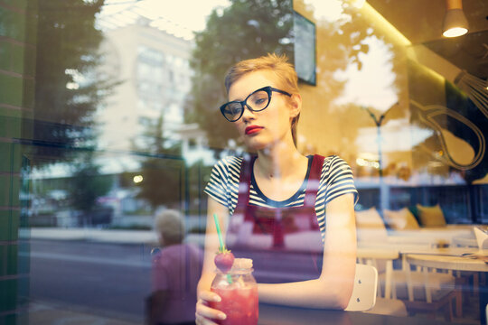 pretty woman with glasses sees a lonely cocktail drink in a cafe