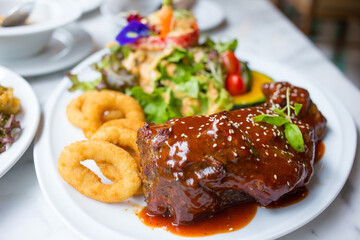 Grilled pork ribs with barbecue sauce and vegetables on a white plate