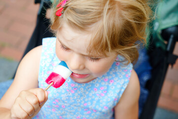 Little preschool girl with lollipop. Cute happy toddler child licking sweet sugar lolli. Happy child with candy.