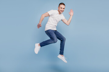 Fototapeta na wymiar Full body profile side photo of cheerful brown haired attractive man jumping running waving hello isolated over blue color background