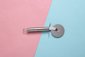 Steel round knife for cutting pizza on pink blue background