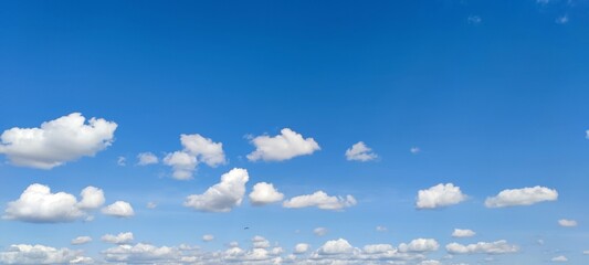 Small cumulus clouds in the clear sky. Against the background of a blue clear sky, on a summer day,...