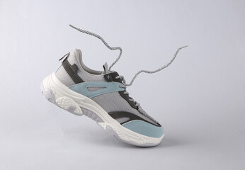 Sports sneaker with flying laces on gray background