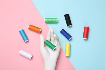 Hand holding Skeins of colored thread on blue-pink pastel background