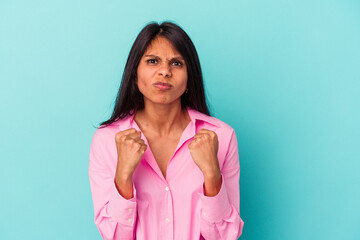 Young latin woman isolated on blue background showing fist to camera, aggressive facial expression.