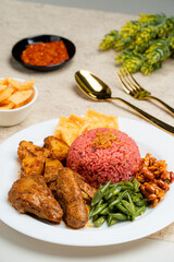 nasi lemak with dragon fruit rice served with chicken rendang and spicy sauce (sambal), sliced fresh chickpeas, small fried anchovies, roasted peanuts.