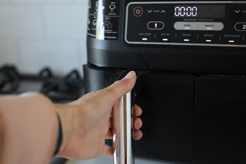 Female caucasian hand opening black air fryer bake drawer kitchen home cook bake fast 