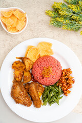 nasi lemak with dragon fruit rice served with chicken rendang and spicy sauce (sambal), sliced fresh chickpeas, small fried anchovies, roasted peanuts.