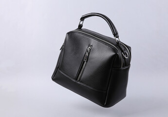 Classic black leather bag levitating on gray background