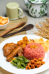 nasi lemak with dragon fruit rice served with chicken rendang and spicy sauce (sambal), sliced fresh chickpeas, small fried anchovies, roasted peanuts.