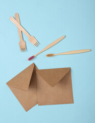 Eco concept. Craft envelope, wooden toothbrushes and forks on blue background