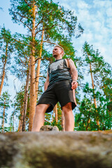 Young man hiking through a pine forest with huge rocks covered with moss