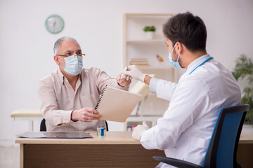 Old male patient visiting young male doctor in vaccination conce