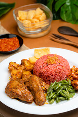 nasi lemak with dragon fruit rice served with chicken rendang and spicy sauce (sambal), sliced fresh chickpeas, small fried anchovies, roasted peanuts.