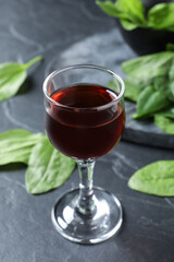 Glass of broadleaf plantain tincture on grey table