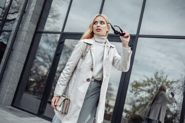 Portrait of an attractive fashion woman in a trench coat near the business center
