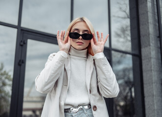 Portrait of an attractive fashion woman in a trench coat near the business center