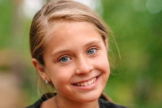 Portrait of a  little girl with blue eyes a natural green background