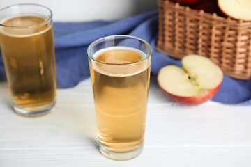 Glasses of delicious apple cider on white table