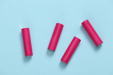Four pink AA batteries on blue background. Top view